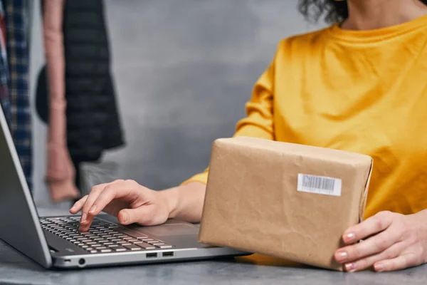 Una donna che manda pacchi usando il suo portatile. Lavorare da casa — Foto Stock