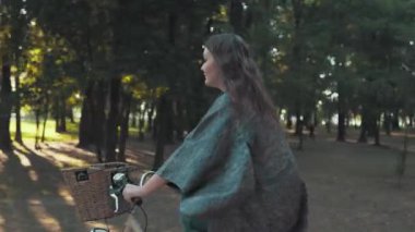 Güneşli bir sabahta parkta bisiklet süren bir kadın.