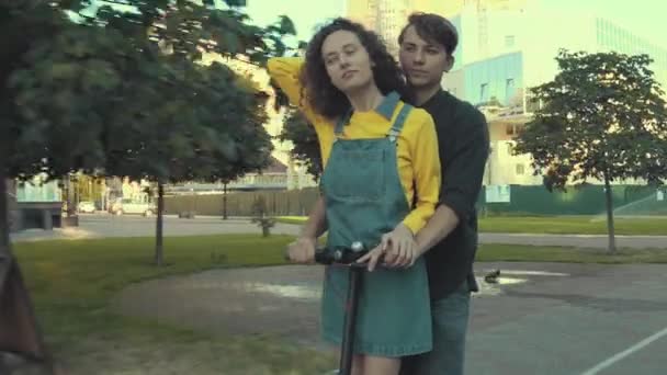 Junges Paar fährt mit Elektroroller in Park — Stockvideo