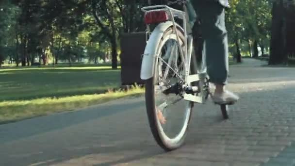Primer plano de la mujer montar en bicicleta de la ciudad en el parque en la mañana soleada — Vídeo de stock