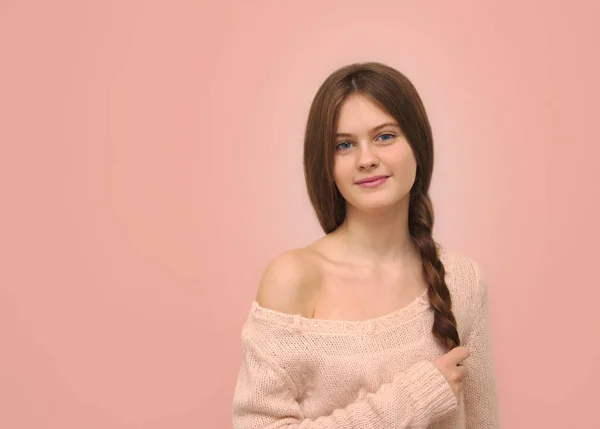 bir örgü pembe bir arka plan üzerinde elinde tutan kahverengi saçlı utangaç kız