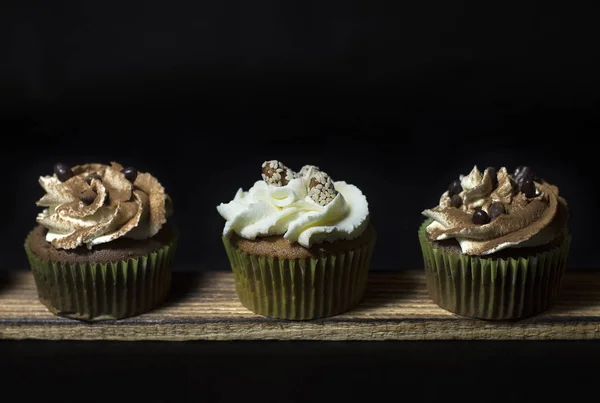 Beleuchtete Cupcakes Auf Einem Holzbrett Vor Schwarzem Hintergrund — Stockfoto