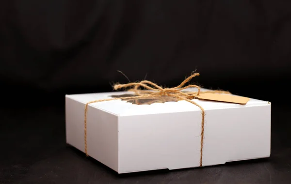 white box with a transparent cover, tied with a rope, with cookies and a label for text on a dark background. A gift for Valentine\'s Day, Mother\'s Day, Birthday