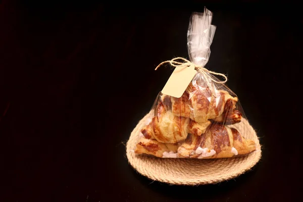 Siyah bir tabloda bir etiketle şeffaf selofan torba doldurma ile taze ev yapımı Fransız kruvasan