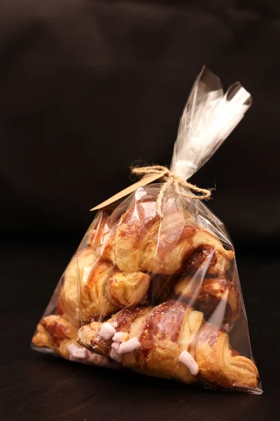 Siyah bir tabloda bir etiketle şeffaf selofan torba doldurma ile taze ev yapımı Fransız kruvasan