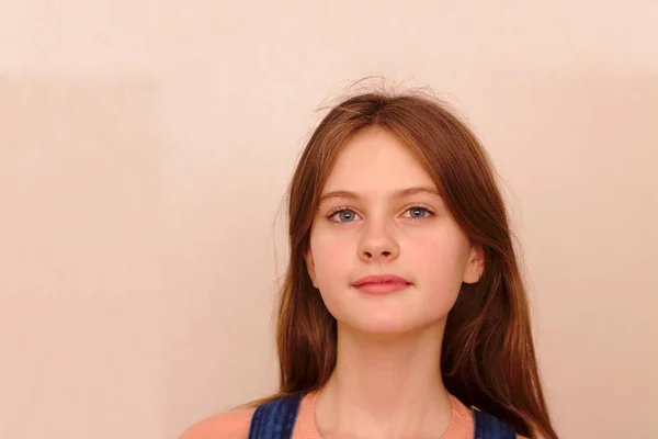 Blue eyed brown haired shy girl in denim overalls. Studio model shot. — Stock Photo, Image