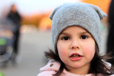 Gün batımı ışığında kentsel manzara nın arka planında şapka lı ve paltolu güzel bir kızın akşam portresi.