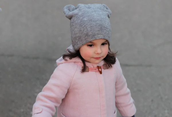 Meglepett kis fehér lány sétál az utcán az esti órákban. Portré a háttérben a naplemente városkép — Stock Fotó