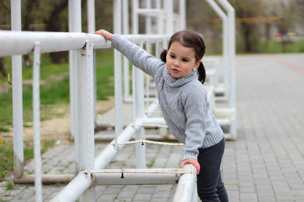 Klein meisje met staartjes in een trui speelt op de bouwplaats — Stockfoto