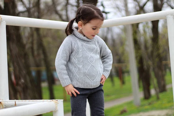 Klein meisje met staartjes in een trui speelt op de bouwplaats — Stockfoto