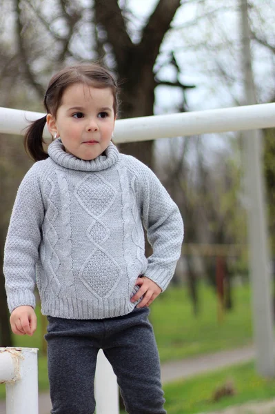 Маленькая девочка с косичками в свитере играет на стройке — стоковое фото