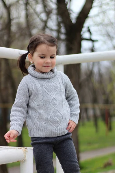 Little girl with pigtails in a sweater plays at the construction site — Stock Photo, Image