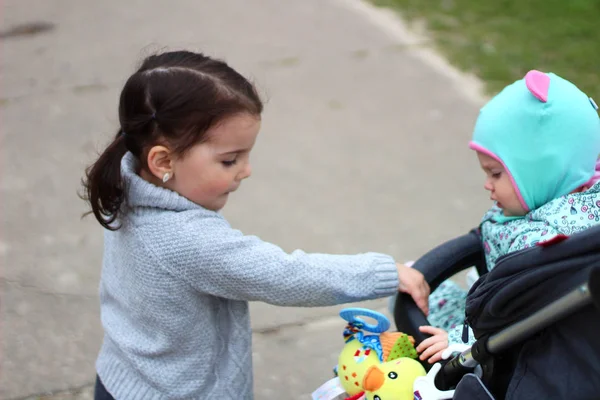 Klein meisje houdt haar zus hand in de Pram — Stockfoto