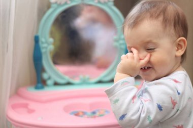 küçük bir çocuk kreşte bir oyuncak ayna önünde oynar