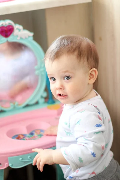 Ein kleines Kind spielt im Kinderzimmer vor einem Spielzeugspiegel — Stockfoto