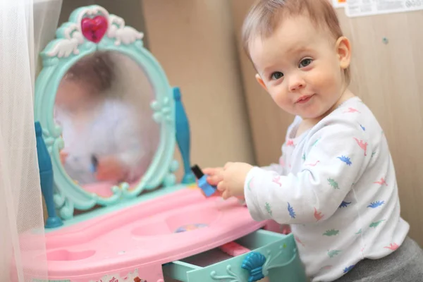Ein kleines Kind spielt im Kinderzimmer vor einem Spielzeugspiegel — Stockfoto