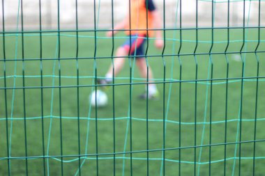 Bölüm yeşil çit odaklı görüntü. Bir top ile futbolcular arka planda oynar.