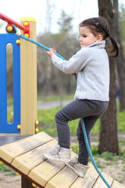 bir çocuk oyun alanında bir ip tırmanıyor