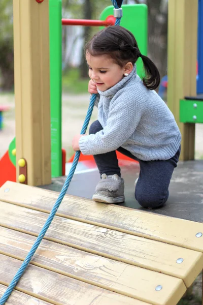 Un niño está escalando una cuerda floja en el patio de recreo —  Fotos de Stock