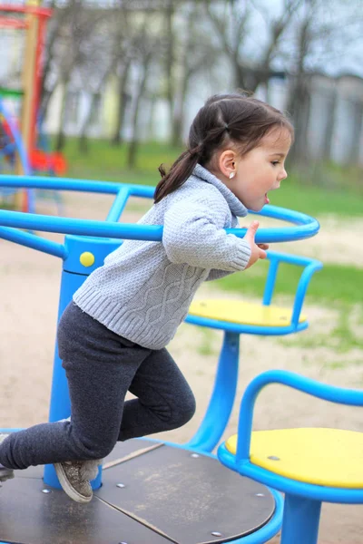 Niño monta en el carrusel en el patio de recreo —  Fotos de Stock