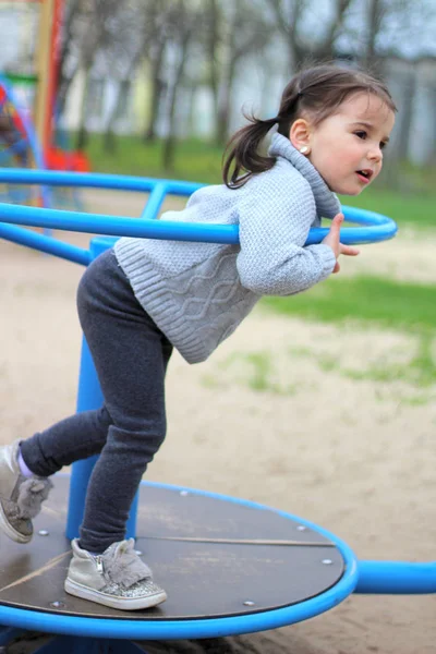 Niño monta en el carrusel en el patio de recreo —  Fotos de Stock