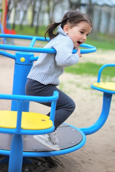 Niño monta en el carrusel en el patio de recreo —  Fotos de Stock