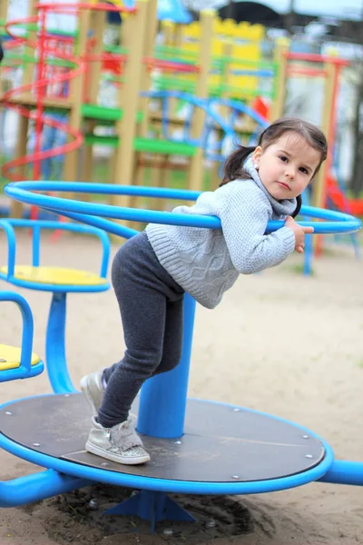 Niño monta en el carrusel en el patio de recreo —  Fotos de Stock