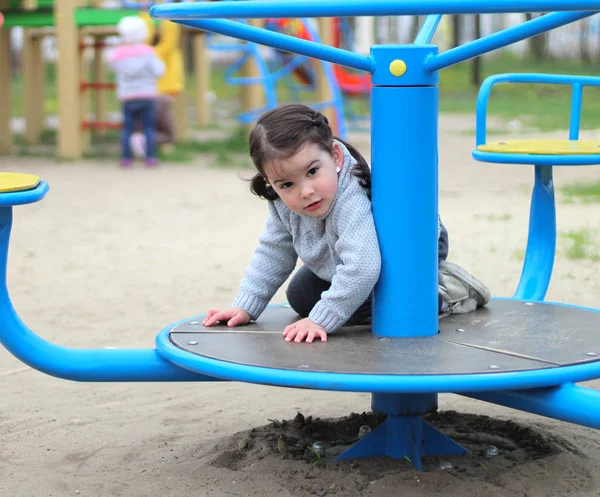 Niño monta en el carrusel en el patio de recreo —  Fotos de Stock