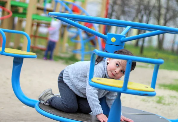 Niño monta en el carrusel en el patio de recreo —  Fotos de Stock