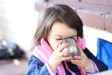 sıcak giyinmiş kız bir metal fincan açık havada içme