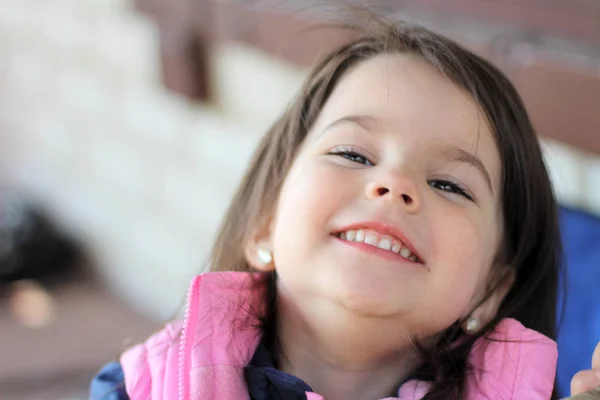 Menina sorrindo sentado na mesa ao ar livre — Fotografia de Stock