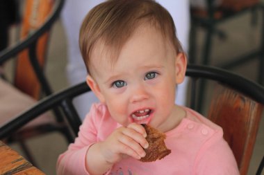 güzel bir sevimli kızıl saçlı çocuğun portresi bir kafede bir masada oturan ve plastik bir şişe den içme suyu