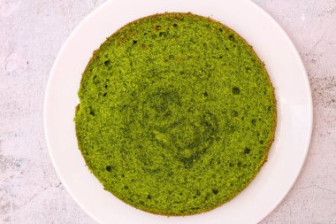 beton bir arka plan üzerinde beyaz bir tabak üzerinde yeşil yuvarlak ıspanak nane kek