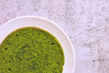 beton bir arka plan üzerinde beyaz bir tabak üzerinde yeşil yuvarlak ıspanak nane kek