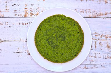 eskip panoları ile masada beyaz bir tabak üzerinde yeşil yuvarlak ıspanak nane kek