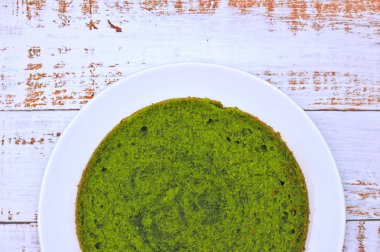 eskip panoları ile masada beyaz bir tabak üzerinde yeşil yuvarlak ıspanak nane kek