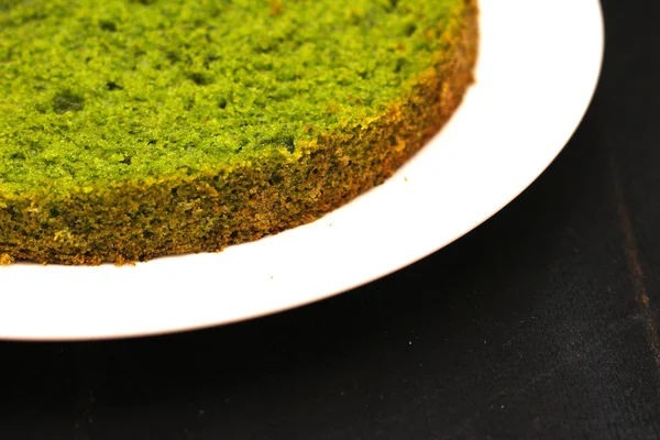 Gâteau à la menthe vert aux épinards ronds sur une assiette blanche sur un fond noir — Photo