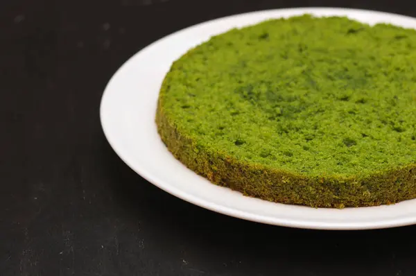 Gâteau à la menthe vert aux épinards ronds sur une assiette blanche sur un fond noir — Photo