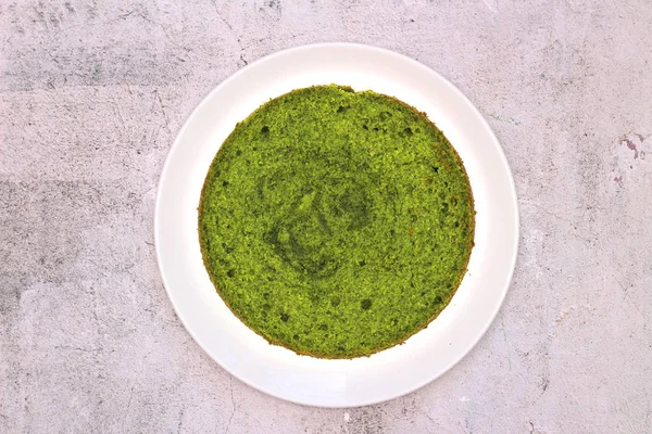 Torta di menta spinaci rotondo verde su un piatto bianco su uno sfondo di cemento — Foto Stock