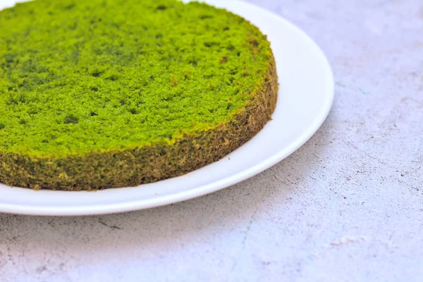 Gâteau à la menthe vert aux épinards ronds sur une assiette blanche sur un fond de béton — Photo