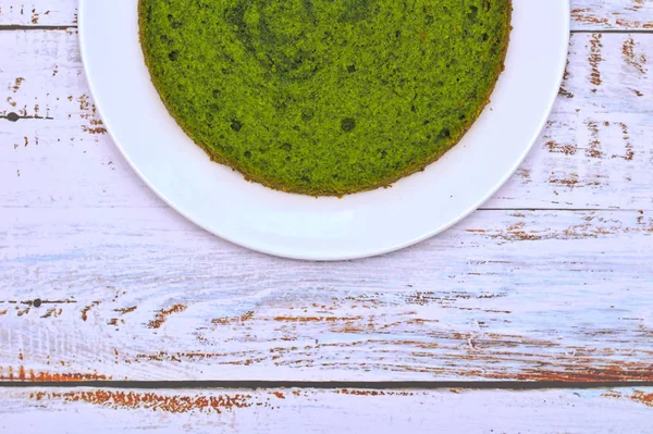 Green round spinach mint cake on a white plate on the table with shabby boards — Stock Photo, Image