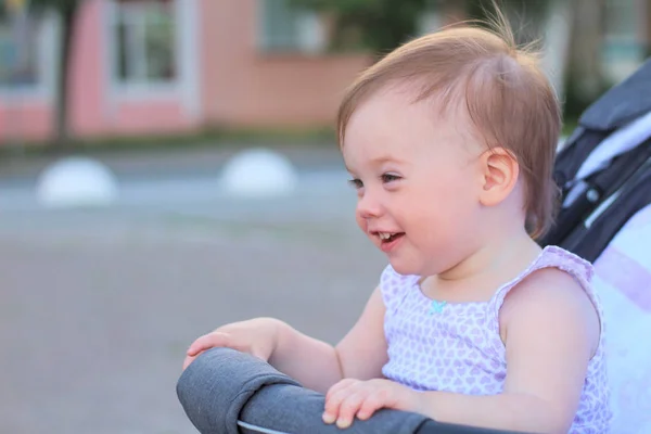 Weinig, mooie, glimlachend, schattige roodharige baby in een kinderwagen out-of-Doors in een mouwloos shirt — Stockfoto