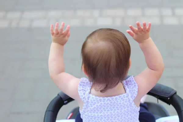 Weinig, mooi, glimlachend, schattige roodharige baby in een mouwloos overhemd in een kinderwagen out-of-Doors verhoogt zijn handen naar voren — Stockfoto