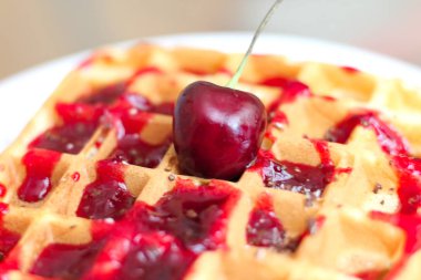 bir tabakta kiraz şurubu ve çikolata cipsi ile lezzetli Belçika waffle. Kırmızı sulu kiraz üst