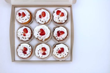 Beyaz kağıt kutusunda taze çilek ve çikolata topları süslenmiş çırpılmış yumurta krema ile Yakın çekim cupcakes