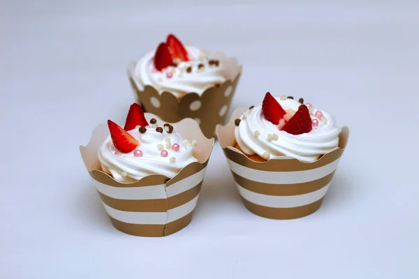 Cupcakes close-up com chantilly ovos creme decorado bolas de morango e chocolate frescos no fundo branco. Isolar — Fotografia de Stock