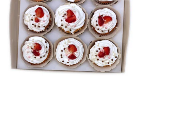 Close-up cupcakes com chantilly ovos creme decorado bolas de morango e chocolate frescos em caixa de papel branco — Fotografia de Stock