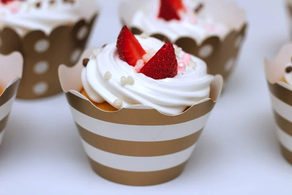 Närbild muffins med vispad ägg grädde dekorerad färsk jordgubb och chokladbollar på vit bakgrund. Isolera — Stockfoto