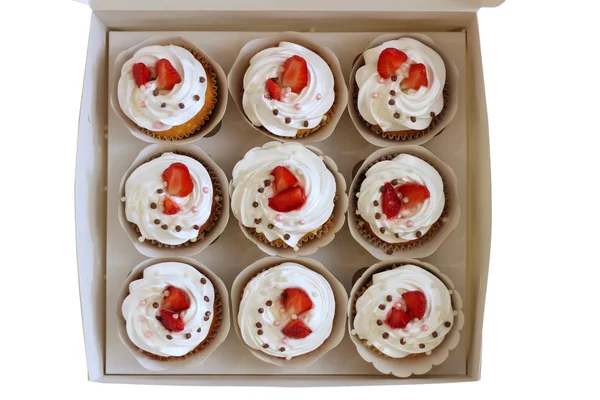 Cupcakes de primer plano con crema de huevos batidos decorados con fresas frescas y bolas de chocolate en caja de papel blanco — Foto de Stock