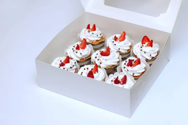 Närbild muffins med vispad ägg grädde dekorerad färsk jordgubb och chokladbollar i vitt papper låda — Stockfoto